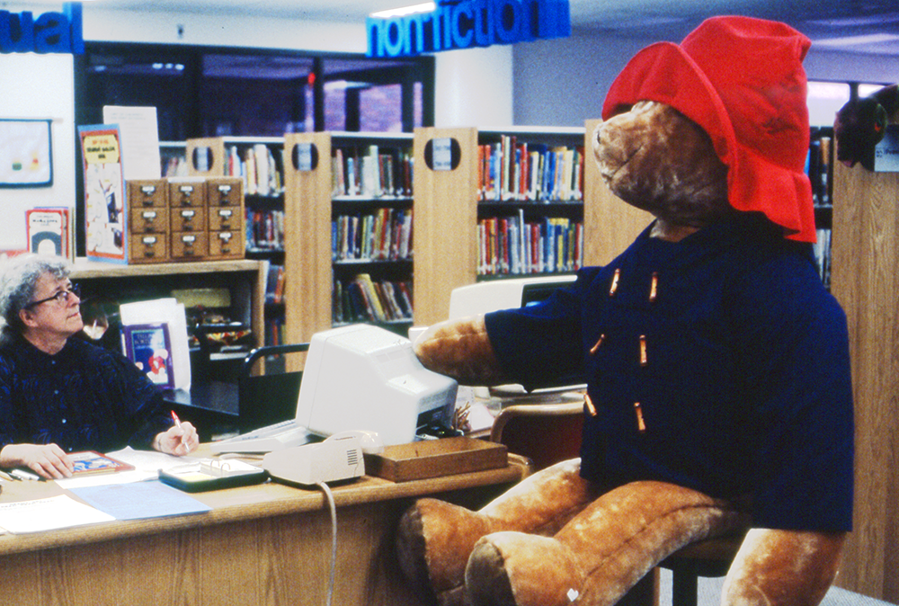 Hazel at desk next to large Paddington Bear