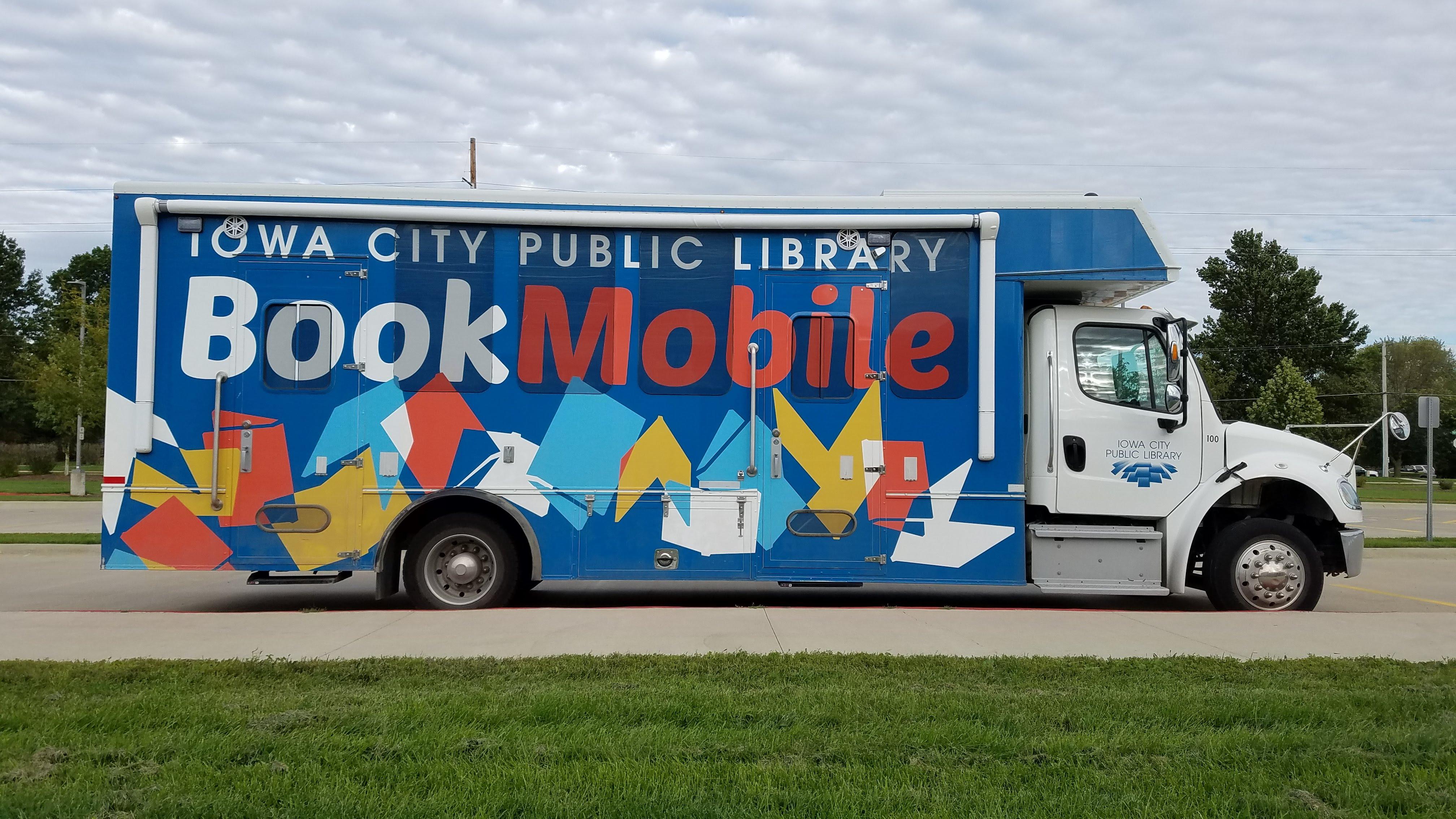 ICPL Bookmobile vehicle parked alongside green grass with cloudy sky.