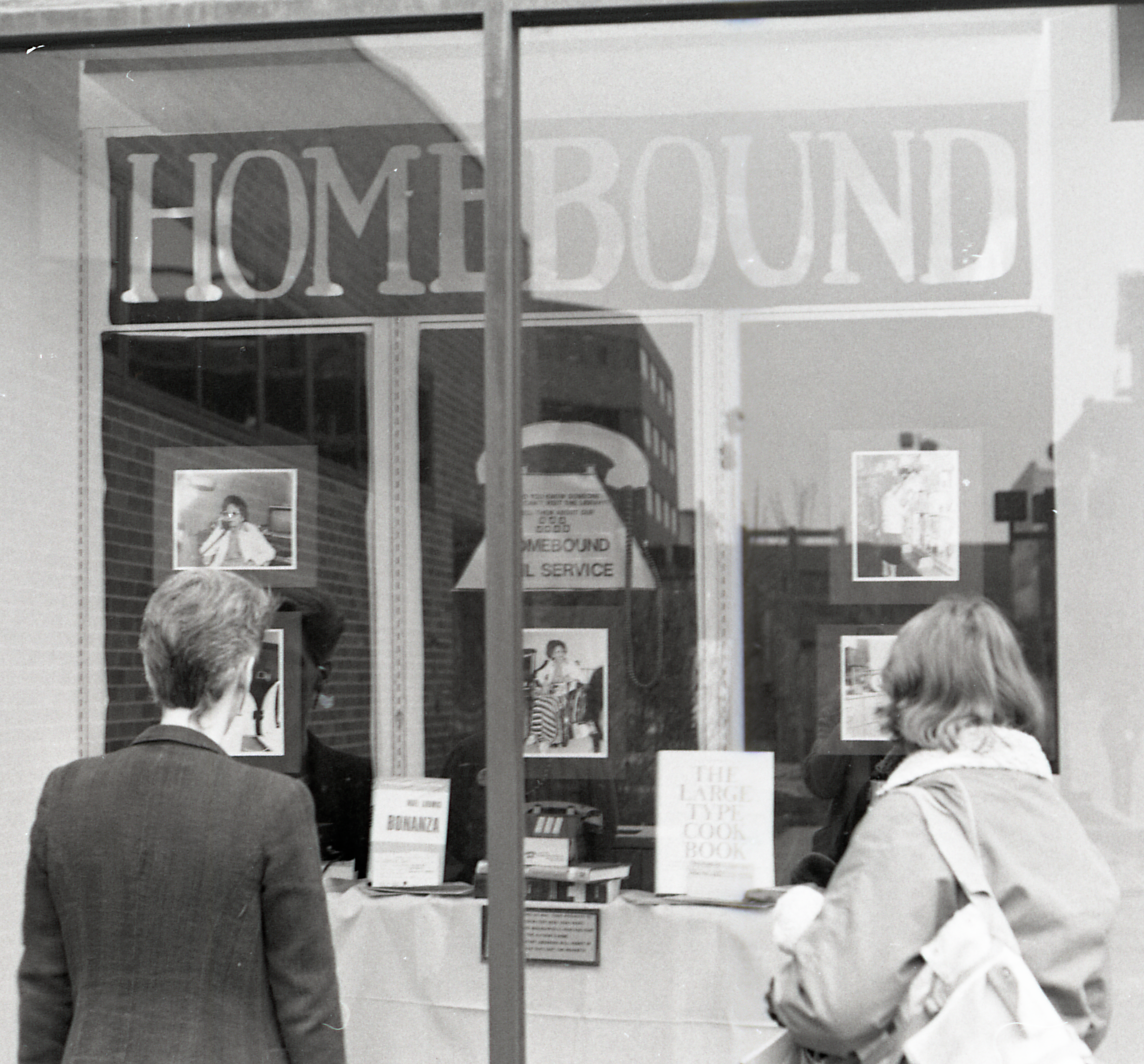 Window with the word "Homebound" displayed in it while two people look on