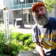 A photo of Scott Koepke from Grow Iowa City next to the Peace Pole in the Iowa City Children's Garden