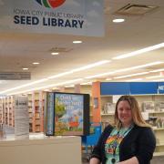 A woman on the second floor of Iowa City Public Library looks through the drawer of a Seed Library. 