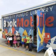 children standing in front of Bookmobile, blue box truck